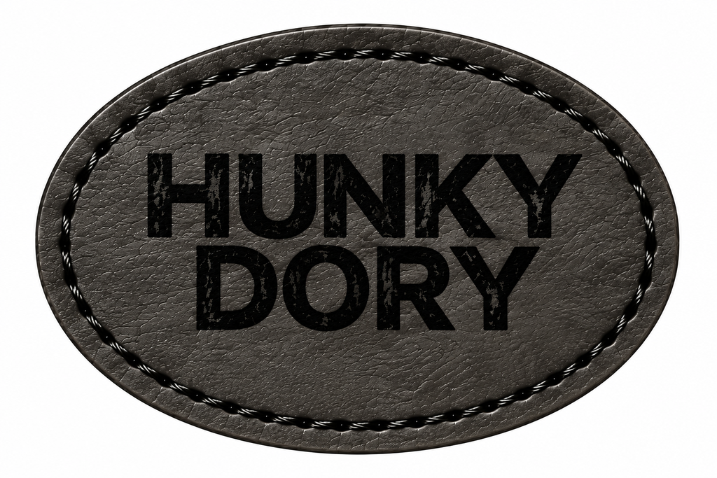 An oval-shaped black patch with black stitched border and the text 'HUNKY DORY' printed in black on a white background.