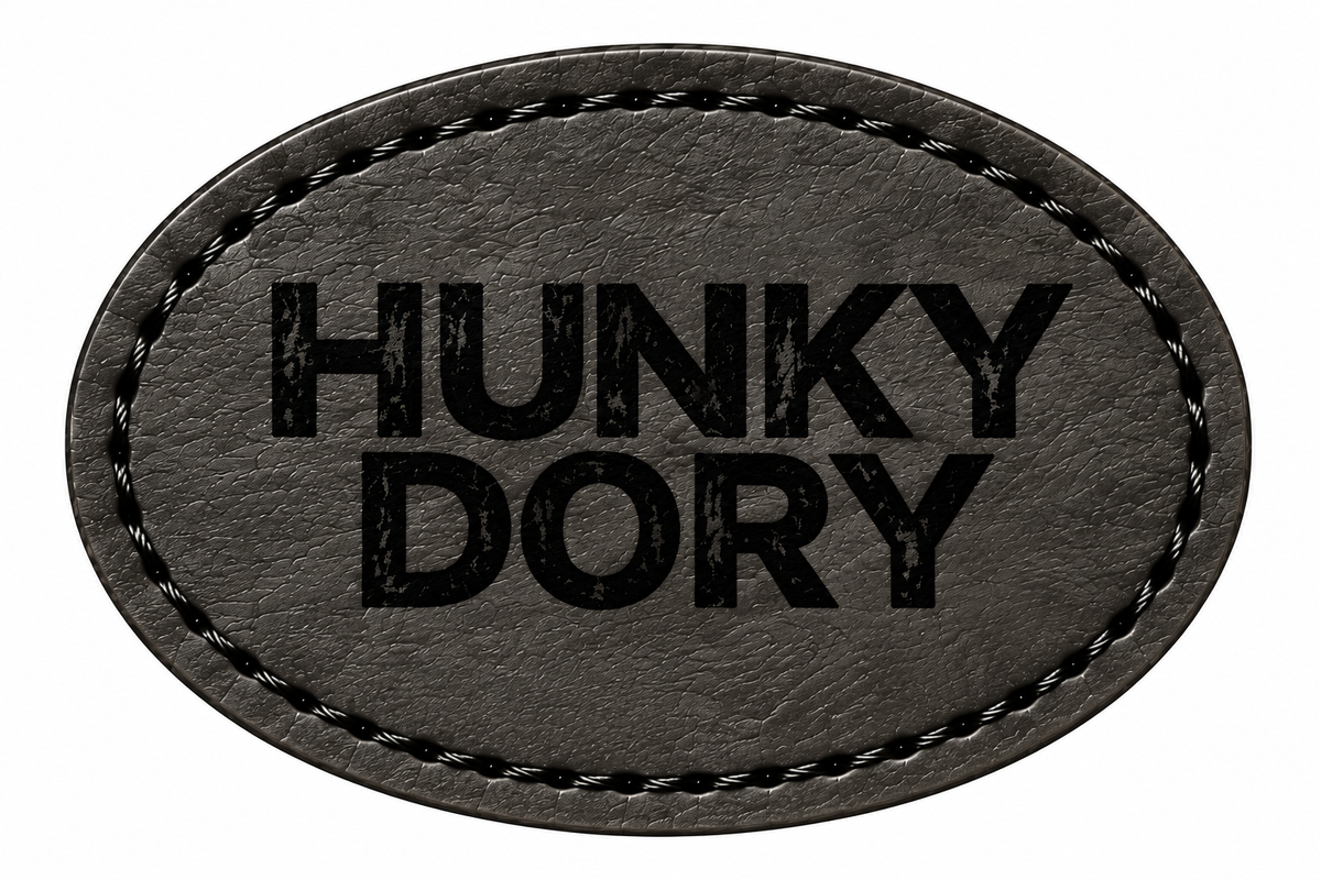 An oval-shaped black patch with black stitched border and the text 'HUNKY DORY' printed in black on a white background.
