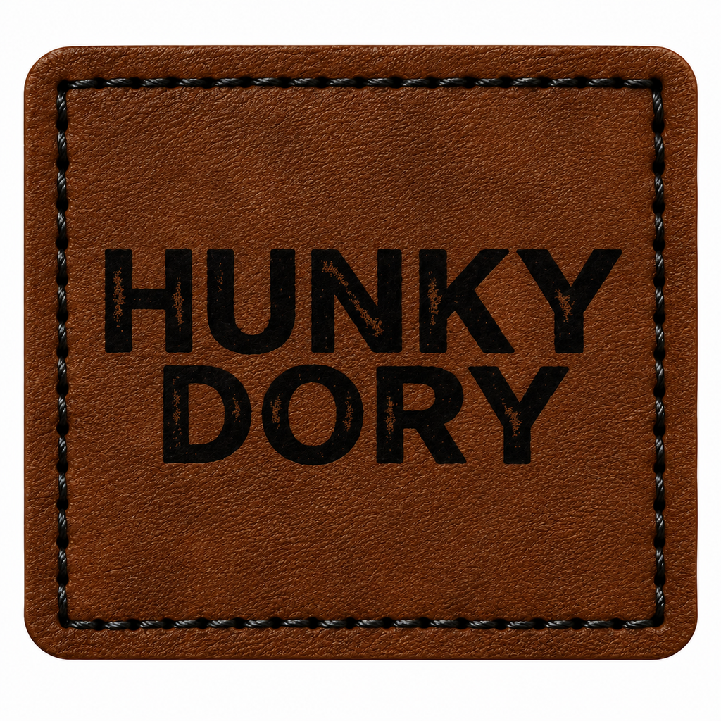 A square brown patch with rounded corners, featuring the words 'HUNKY DORY' printed in bold black capital letters in the center. The patch has a stitched border and is shown against a plain white background.