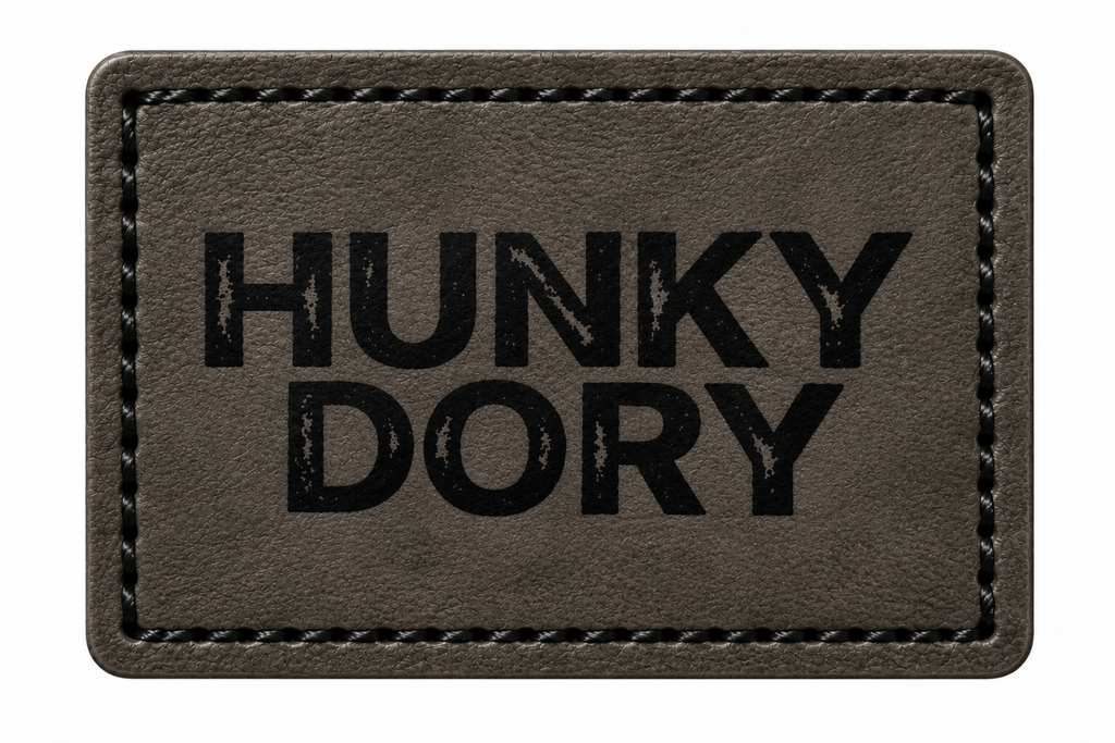 A rectangular black patch with black stitched border and the words 'HUNKY DORY' printed in bold black letters, shown on a plain white background.