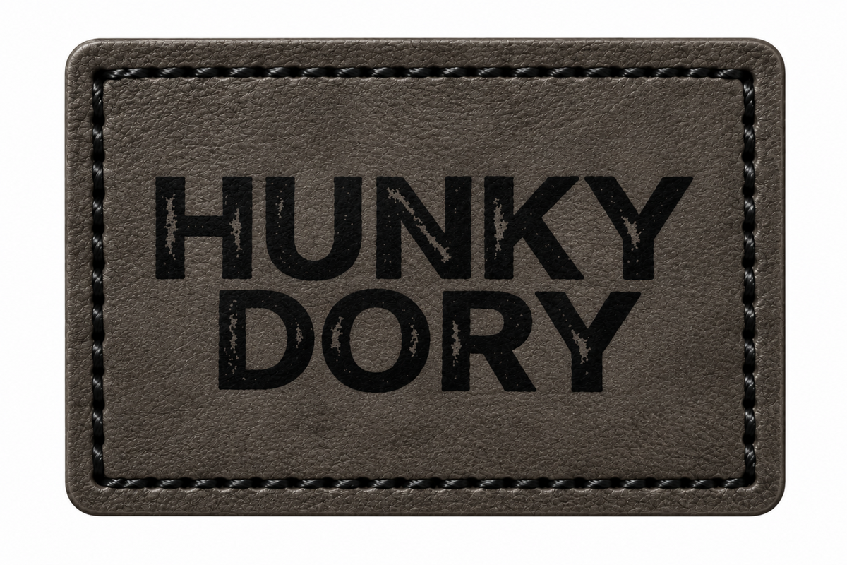 A rectangular black patch with black stitched border and the words 'HUNKY DORY' printed in bold black letters, shown on a plain white background.