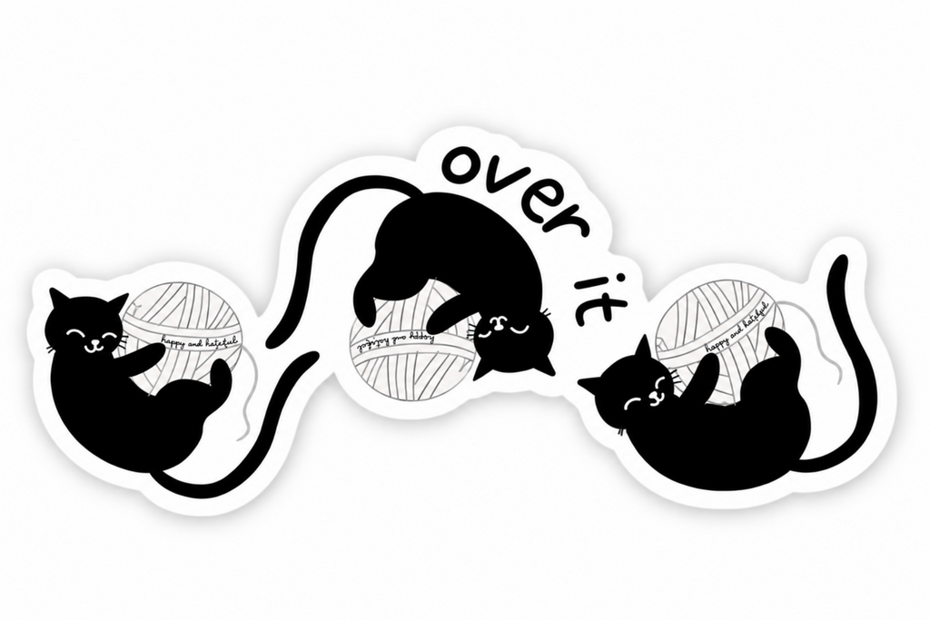 A die-cut vinyl sticker featuring black cartoon cats playing with yarn and the text 'over it'.